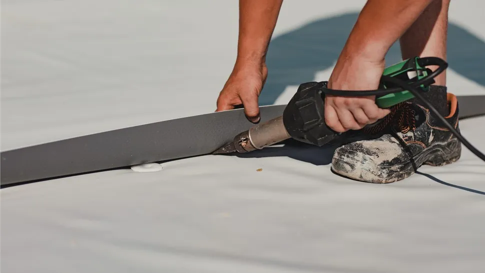 Crew rolling out membrane on a flat commercial roof