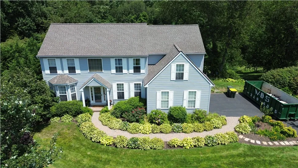 Aerial view of a light blue two-story home with white-trimmed windows