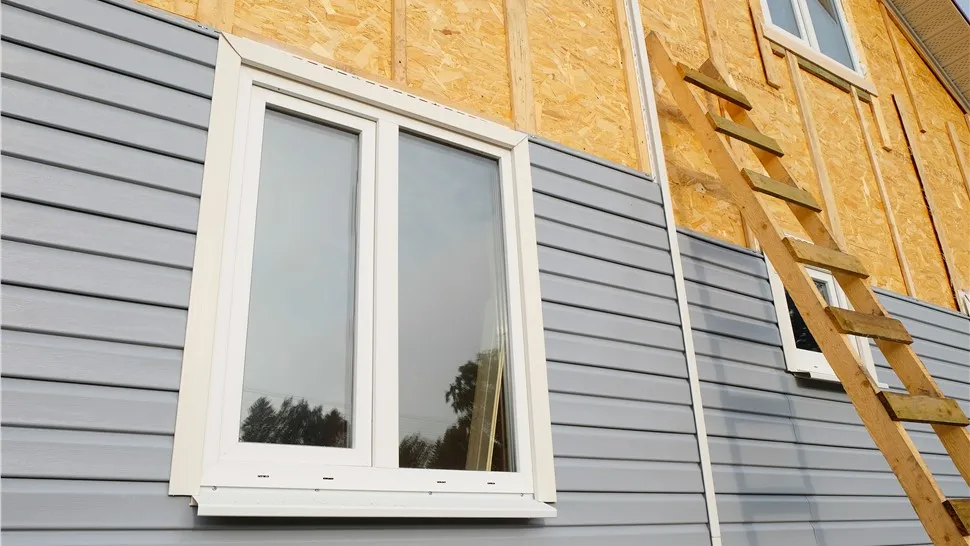 New lap siding and a window being installed over exposed wall sheathing