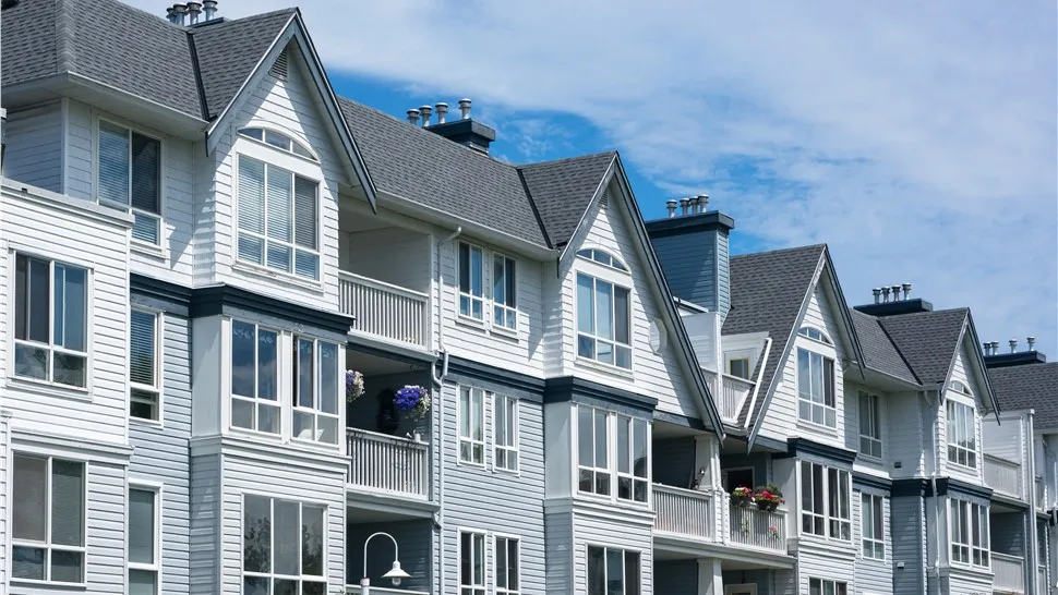 Row of multi-unit buildings with shingled roofs and dormers