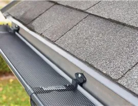 A perforated gutter-guard panel fitted over a gutter at the roof edge
