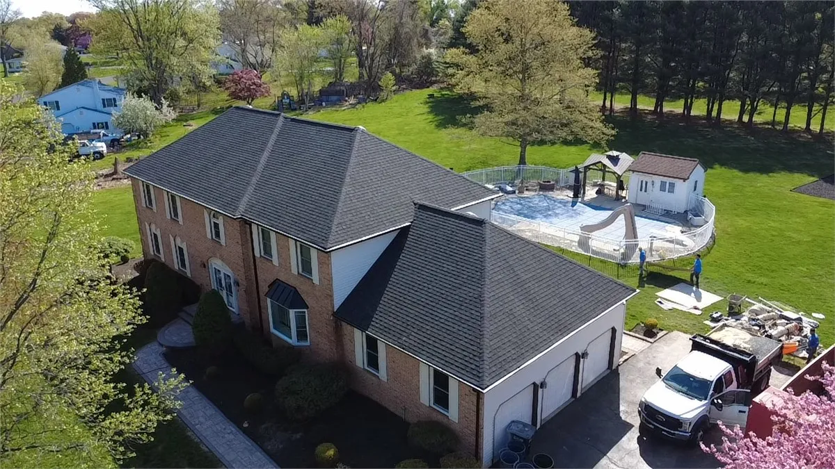 Aerial view of a completed roof replacement on a brick two-story home